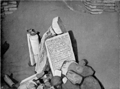 Arabic Inscription and marble columns with earthenware lamps upon them. Fragment of water-pipe. Stone implements. Brick wall of the Tombs of Forty Saints showing in top corners of photograph. Arabic Inscription and marble columns with earthenware lamps upon them. Fragment of water-pipe. Stone implements. Brick wall of the Tombs of Forty Saints showing in top corners of photograph.