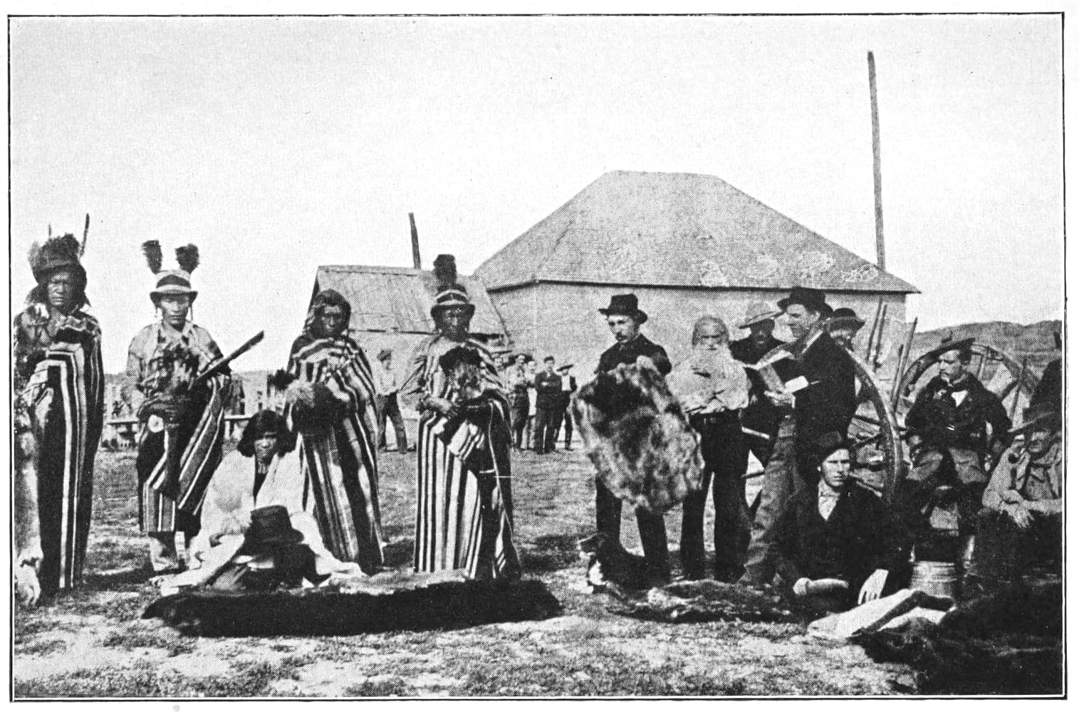 A group of people in front of some dwellings
