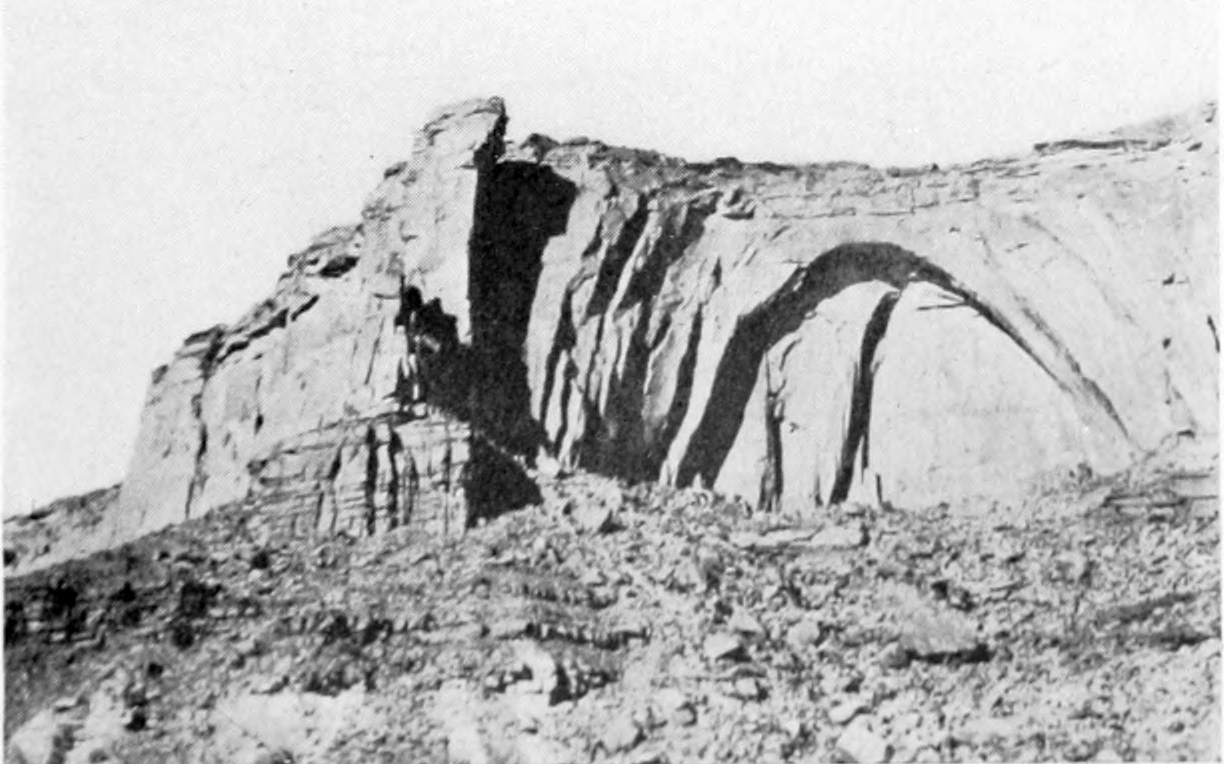 View of an upper canyon face. An arch is formed in the wall where erosion has removed the stone below it.