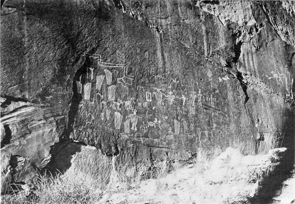 The dark face of a canyon wall is covered with images etched into the stone by earlier Indian inhabitants of the area.