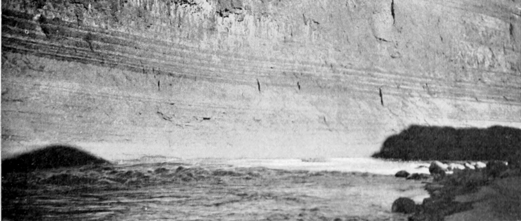 Striations of various widths extend across the width of a sheer canyon wall.