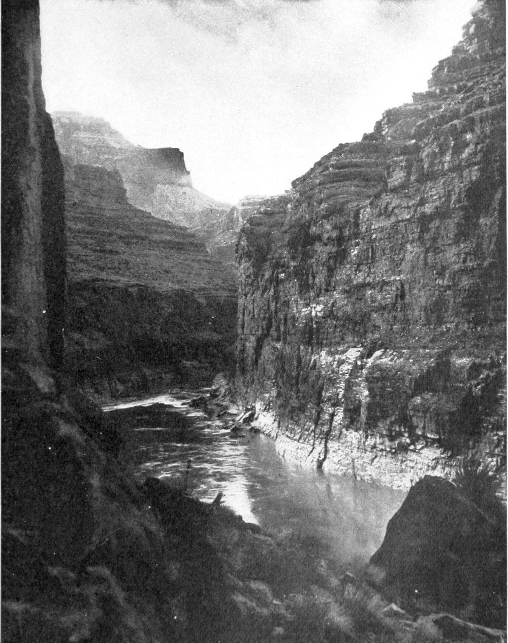 Steep canyon walls rise on both sides of the river. A boat is at the top of a narrow rapids.