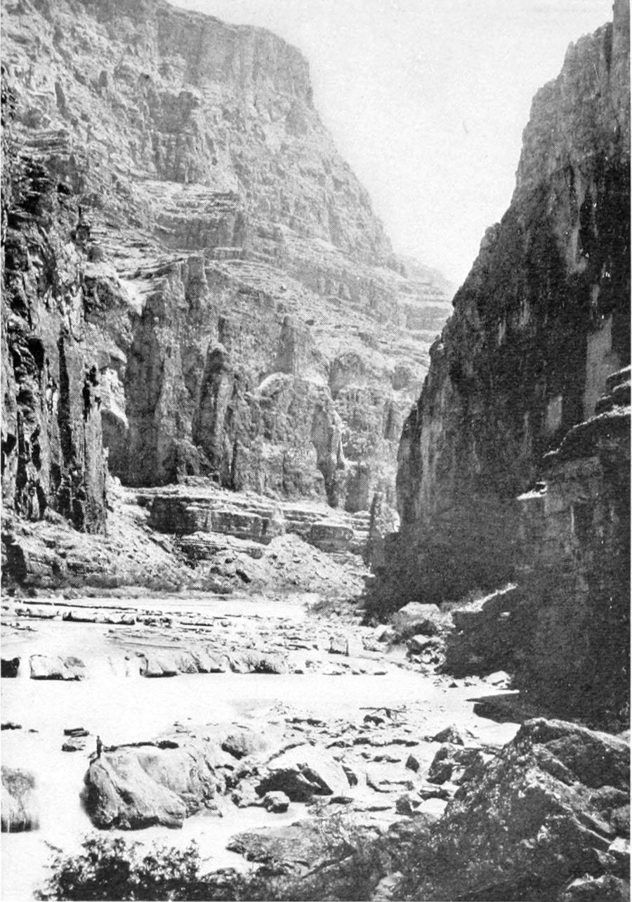 A rock-strewn stretch of river lies between canyon walls.