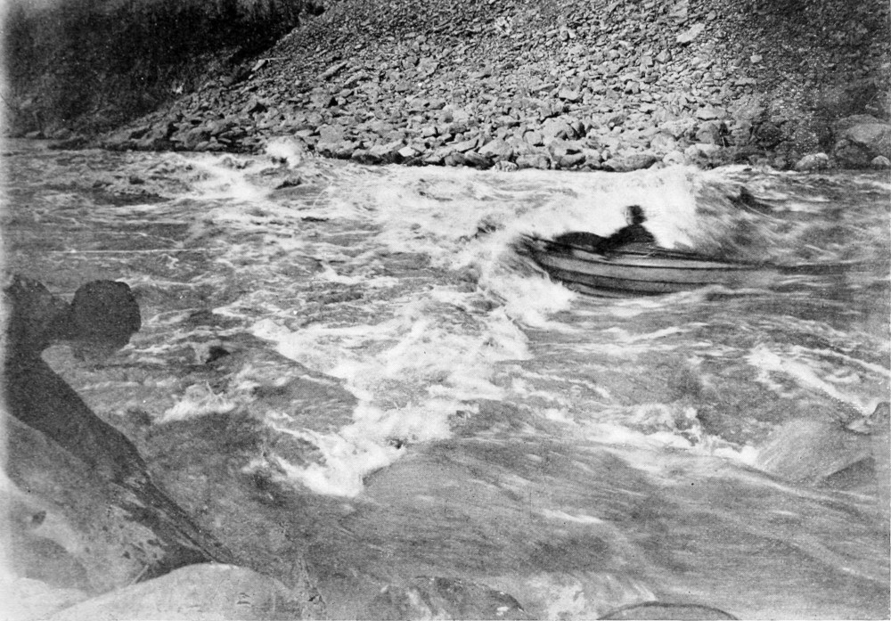 The river water is foamy from the waves; a boat and its passenger ride through it.