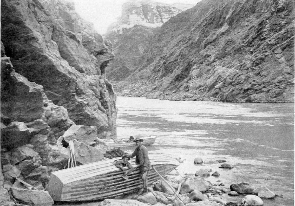 The 'Edith' is tied on a rocky shore, lying on its port side. One man stands beside the boat; another man's head and shoulders appear through a hole in the starboard side of the boat.