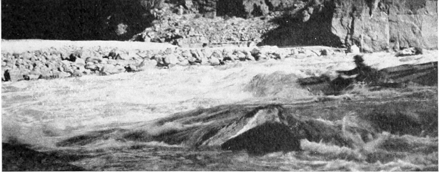Close-up photo of a man in a boat negotiating the river rapids.
