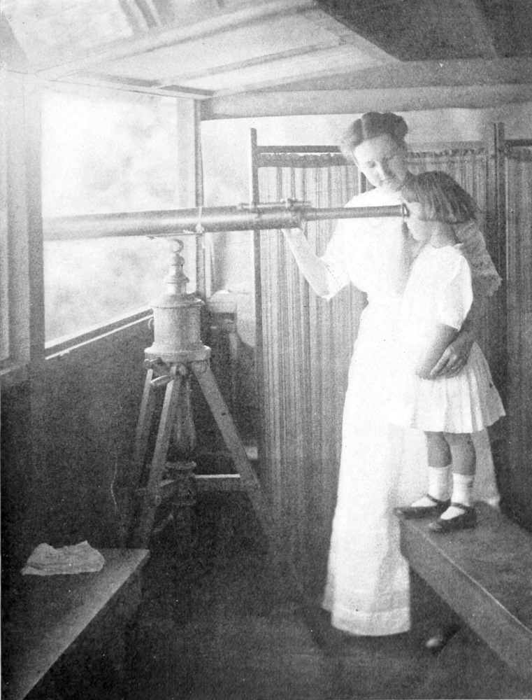 Edith stands on a bench looking through a huge telescope, supported on a tripod, extending out the window. Her mother wraps one arm around Edith's waist and uses the other to balance the telescope.
