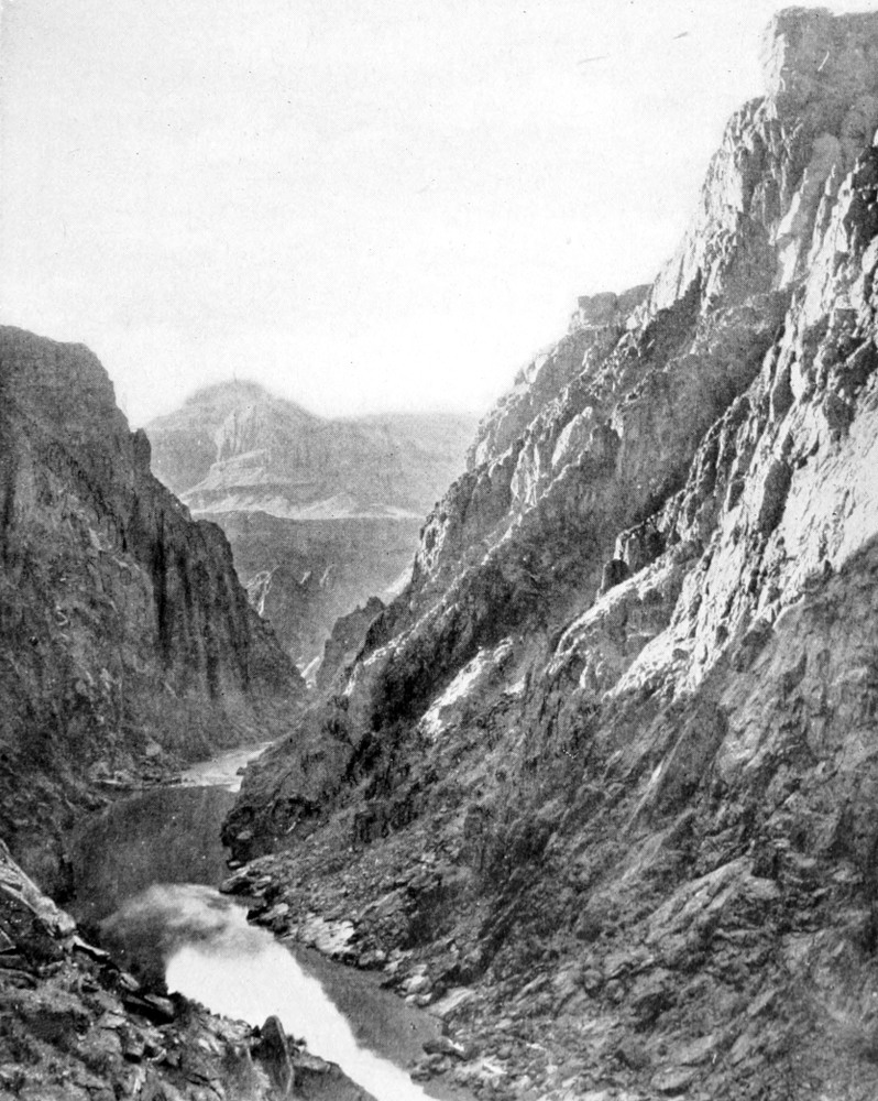 River at the base of jaggged rock cliffs on either side.