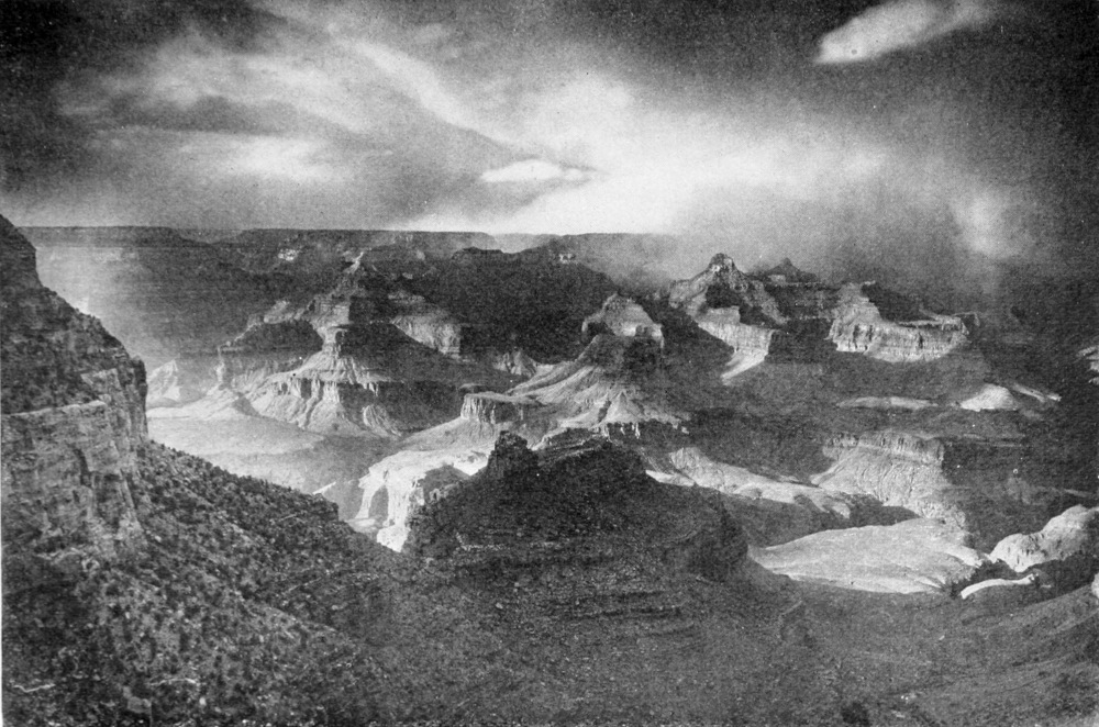 High contrast photo of the top of the canyon. Dramatic lighting of clouds in the sky and canyon peaks below.