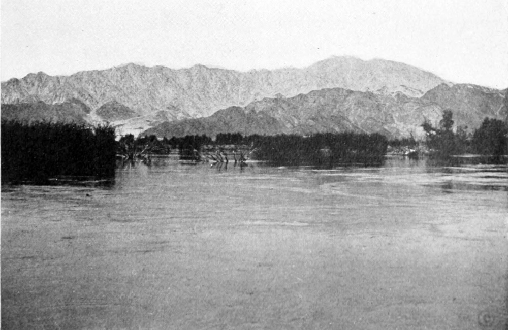 View of a low mountain across a wide, calm lake.
