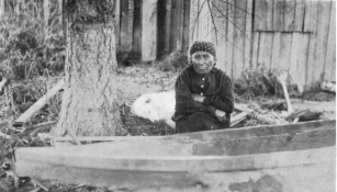 WATERMAN—CANOES PL. IV BOW OF THE HULL SHOWN IN PLATE V, VIEWED FROM THE SIDE, WITH THE MAKE1’S WIFE, MARY ADAMS (TAI´PΔS) SEATED BESIDE IT (Photograph by J. D. Leechman.)