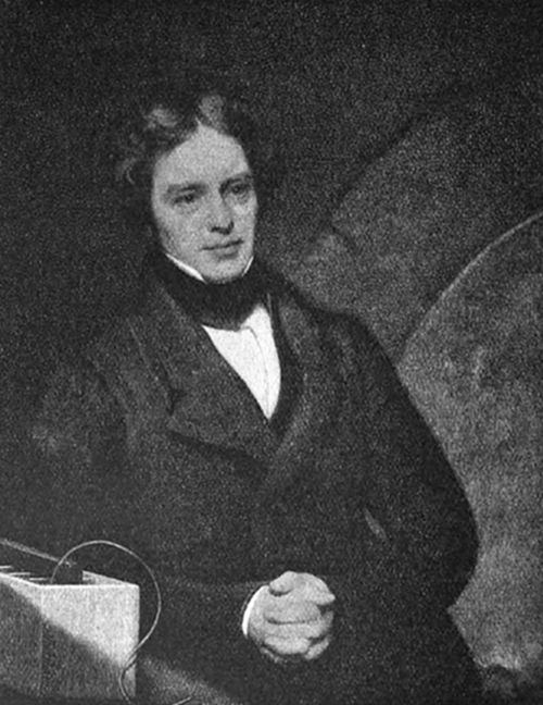A photograph of a young, curly-haired man in early 19th-century dress with a bow tie, seated beside scientific apparatus — consistent with portraits of Michael Faraday, pioneer of electromagnetism and electrochemistry.